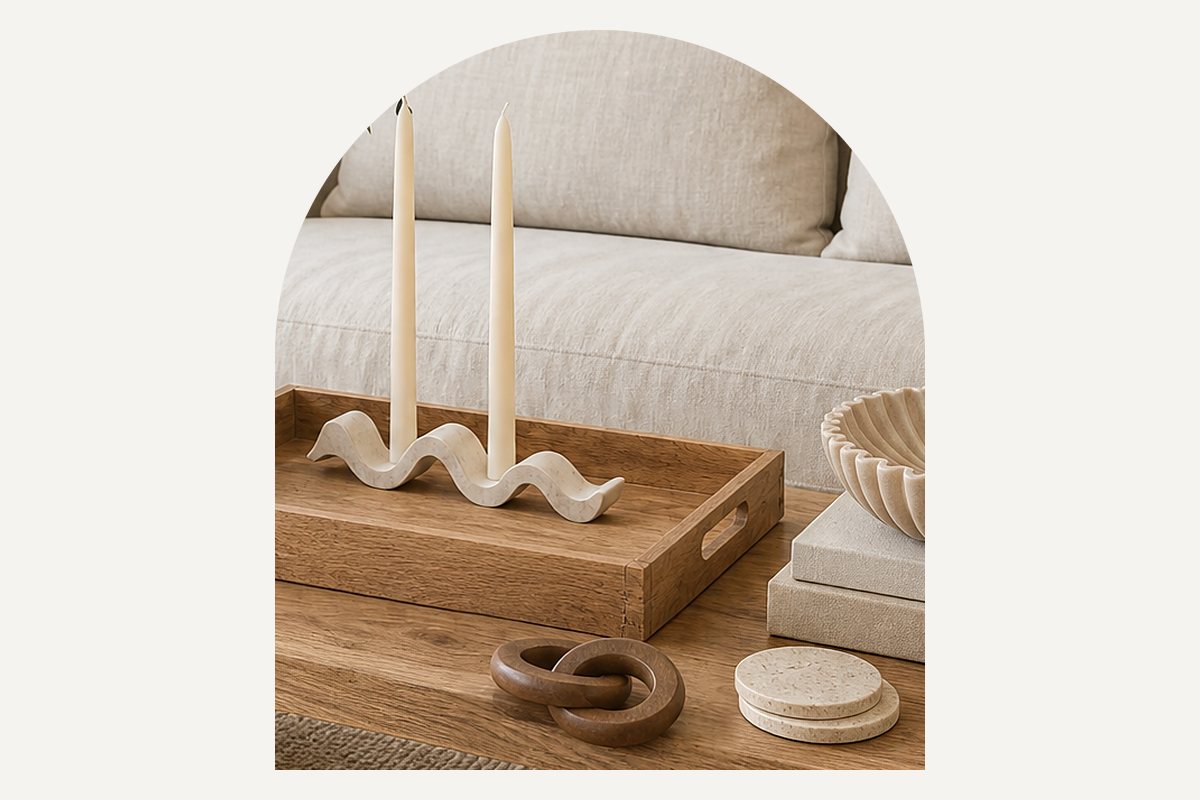 Close-up of a white wave taper candle holder with two ivory tapers on the wood tray, with travertine coasters at the front of the table